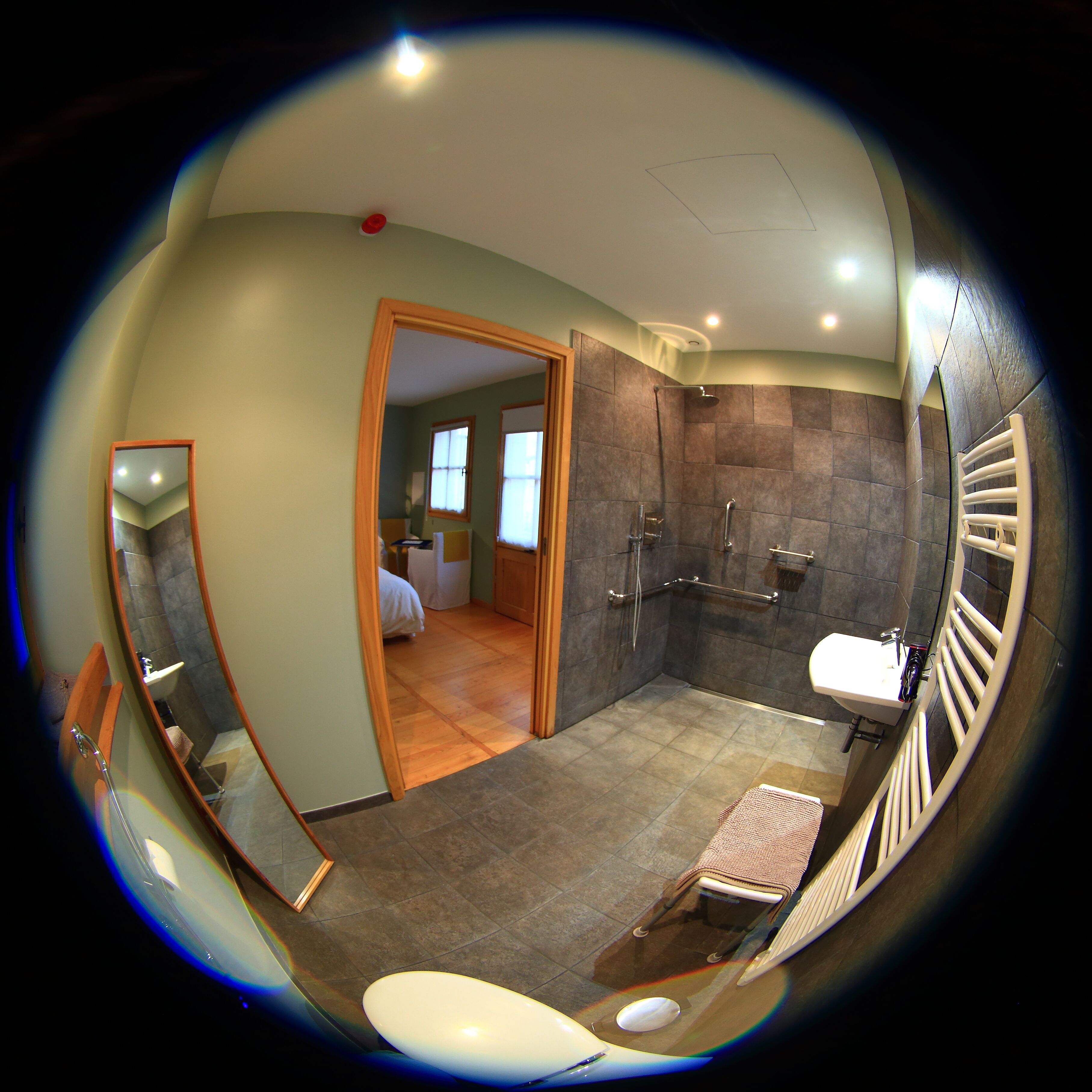 Et panorama over et badeværelse med brusebad, vask og toilet.