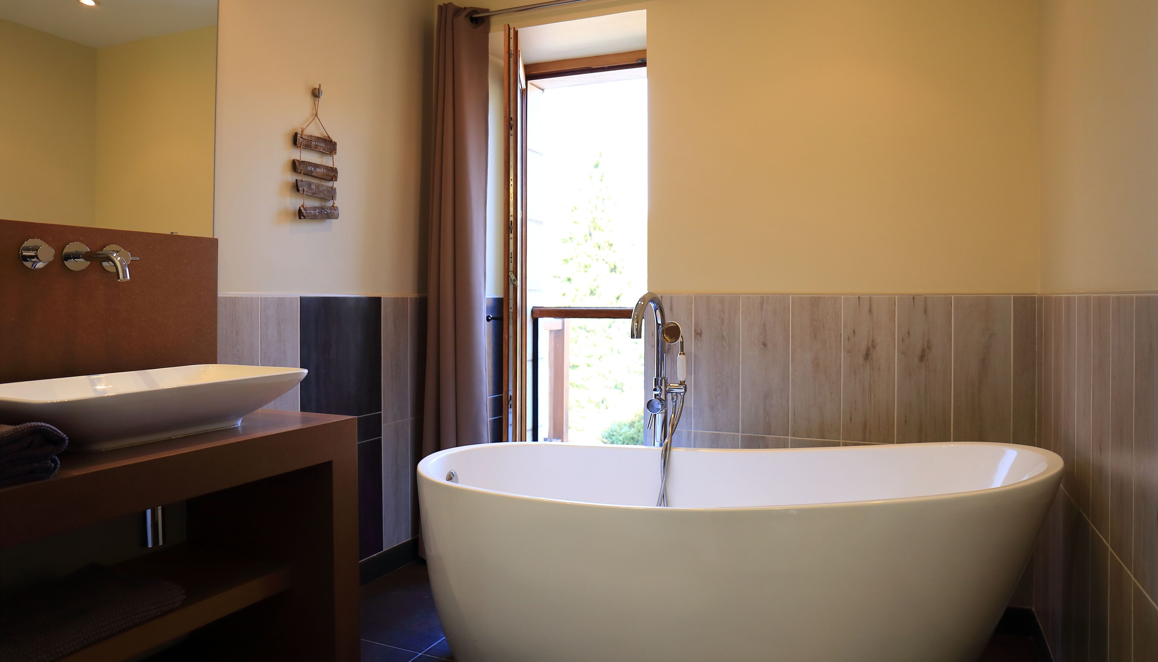 A bathroom with a freestanding bathtub, a sink, and a wooden vanity.