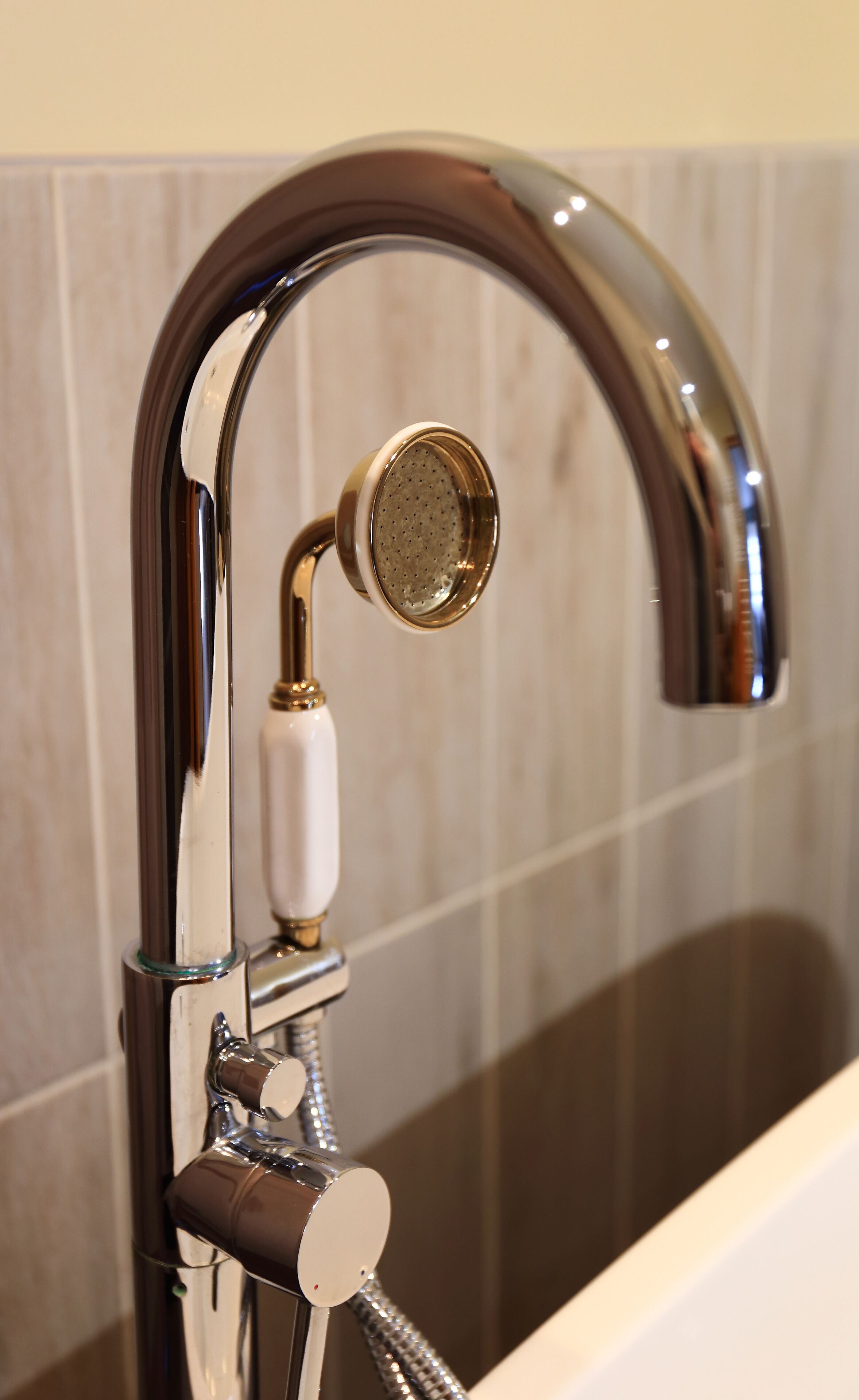 A modern bathroom with a chrome faucet and showerhead, a glass enclosure, and a marble-tiled wall.