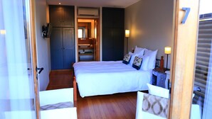 A bedroom with a large bed, bedside tables, a wardrobe, and an air conditioning unit. - Hôtel Restaurant Le Jardin des chouchoux Brantôme  (Brantôme en Périgord)