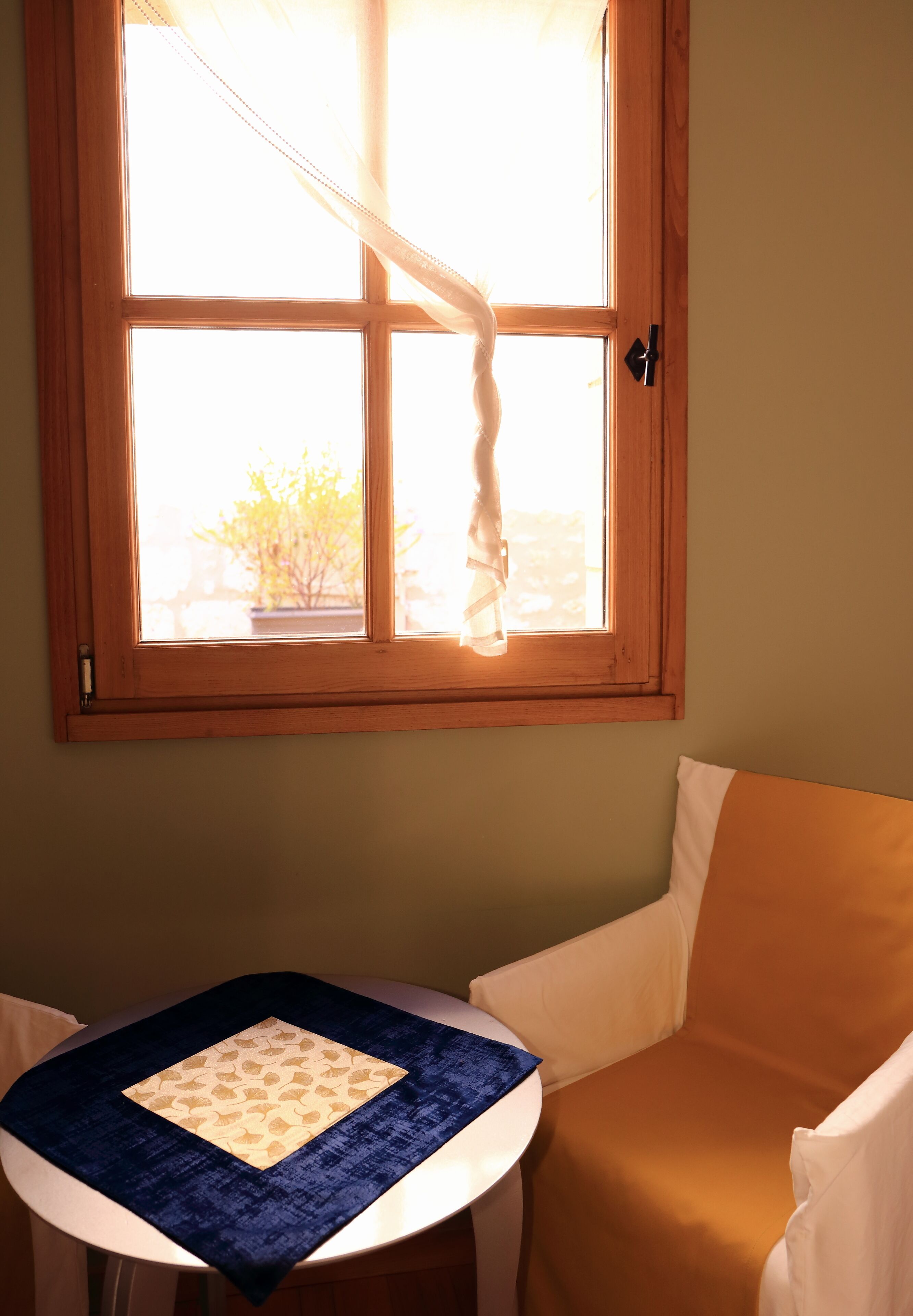 Une pièce avec une fenêtre, une table recouverte d’une nappe bleue et une chaise.