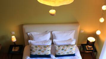 A bed with white bedding and patterned pillows, two bedside tables with lamps, and a hanging light fixture.