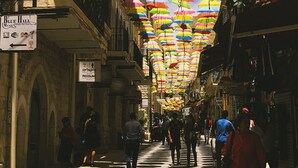 Une rue où des parapluies colorés sont suspendus au-dessus des passants.