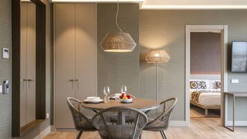 A modern dining area with a round table, wicker chairs, and a bowl of fruit.