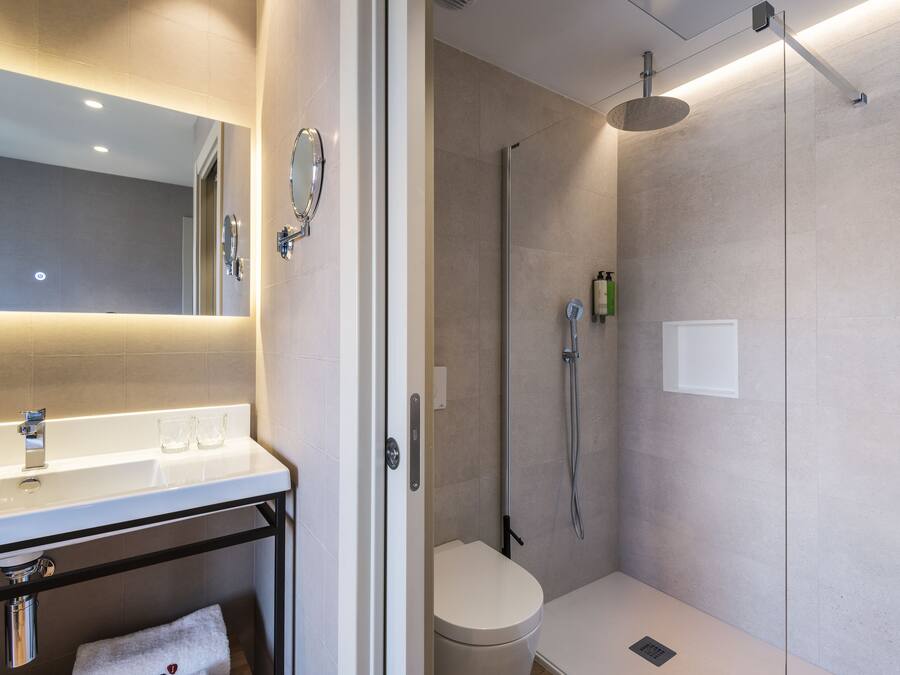 Un baño moderno con un lavabo, espejo y retrete blancos.