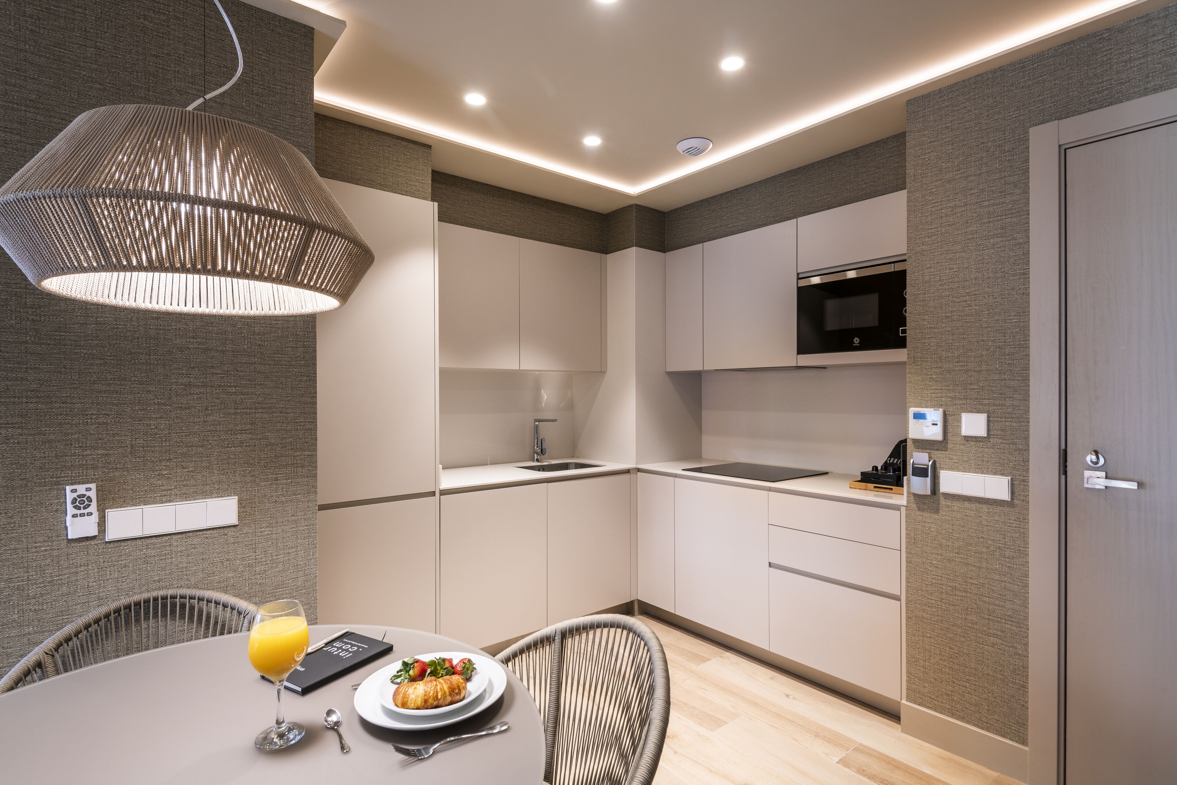 Una cocina moderna con armarios blancos, un microondas y un comedor con mesa y sillas.