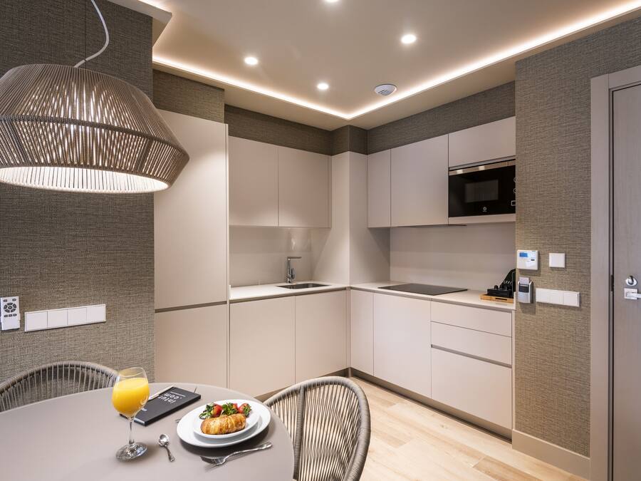 Una cocina moderna con armarios blancos, un microondas y un comedor con mesa y sillas.