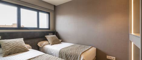 A bedroom with two beds, a window, a ceiling fan, and a wall-mounted light.