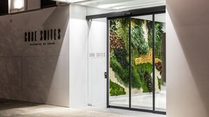 L’entrée d’un hôtel, avec une porte en verre, une enseigne indiquant « CORE SUITES VALENCIA BY INTUR » et un jardin intérieur luxuriant visible à travers le verre.
