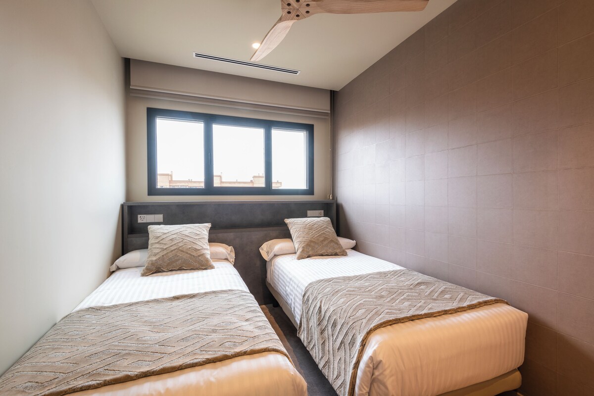 A room with two beds, a window, and a ceiling fan.