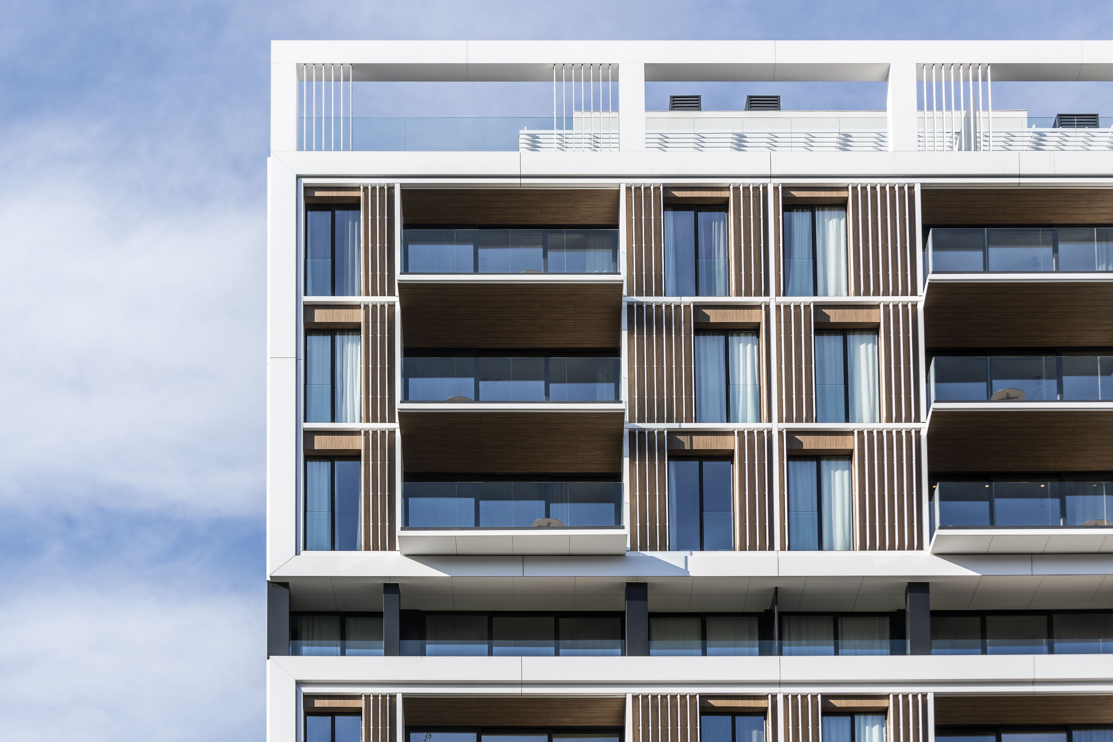Un edificio de varios pisos con un diseño arquitectónico moderno, con balcones y amplias ventanas.