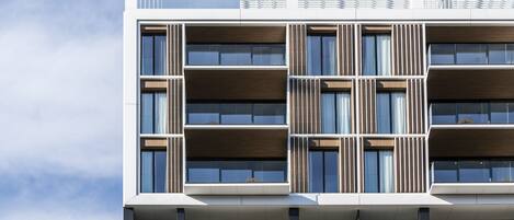 A multi-story building with a modern architectural design, featuring balconies and large windows.