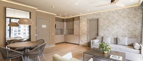 A modern living room with a dining area, a sofa set, and a ceiling fan.
