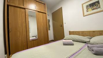 Un dormitorio con cama, armario de madera, puerta y un cuadro en la pared.