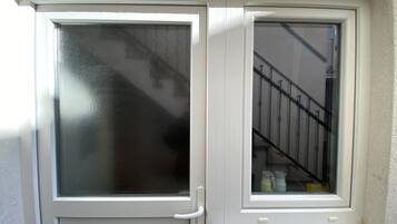 Uma porta branca com painel de vidro fosco e uma pequena janela com um pequeno parapeito de mármore branco abaixo.