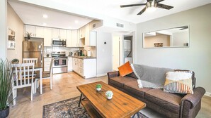 A modern kitchen with white cabinets, stainless steel appliances, and a wooden dining table with chairs. - Rustic 2 Bedroom Canyon Suite Biltmore Camelback (Phoenix)
