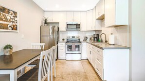 A modern kitchen with white cabinets, stainless steel appliances, a dining table with chairs, and a painting on the wall. - Rustic 2 Bedroom Canyon Suite Biltmore Camelback (Phoenix)