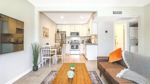 A modern kitchen with white cabinets, a dining area with a wooden table and chairs, and a cozy seating area with a sofa and cushions. - Rustic 2 Bedroom Canyon Suite Biltmore Camelback (Phoenix)