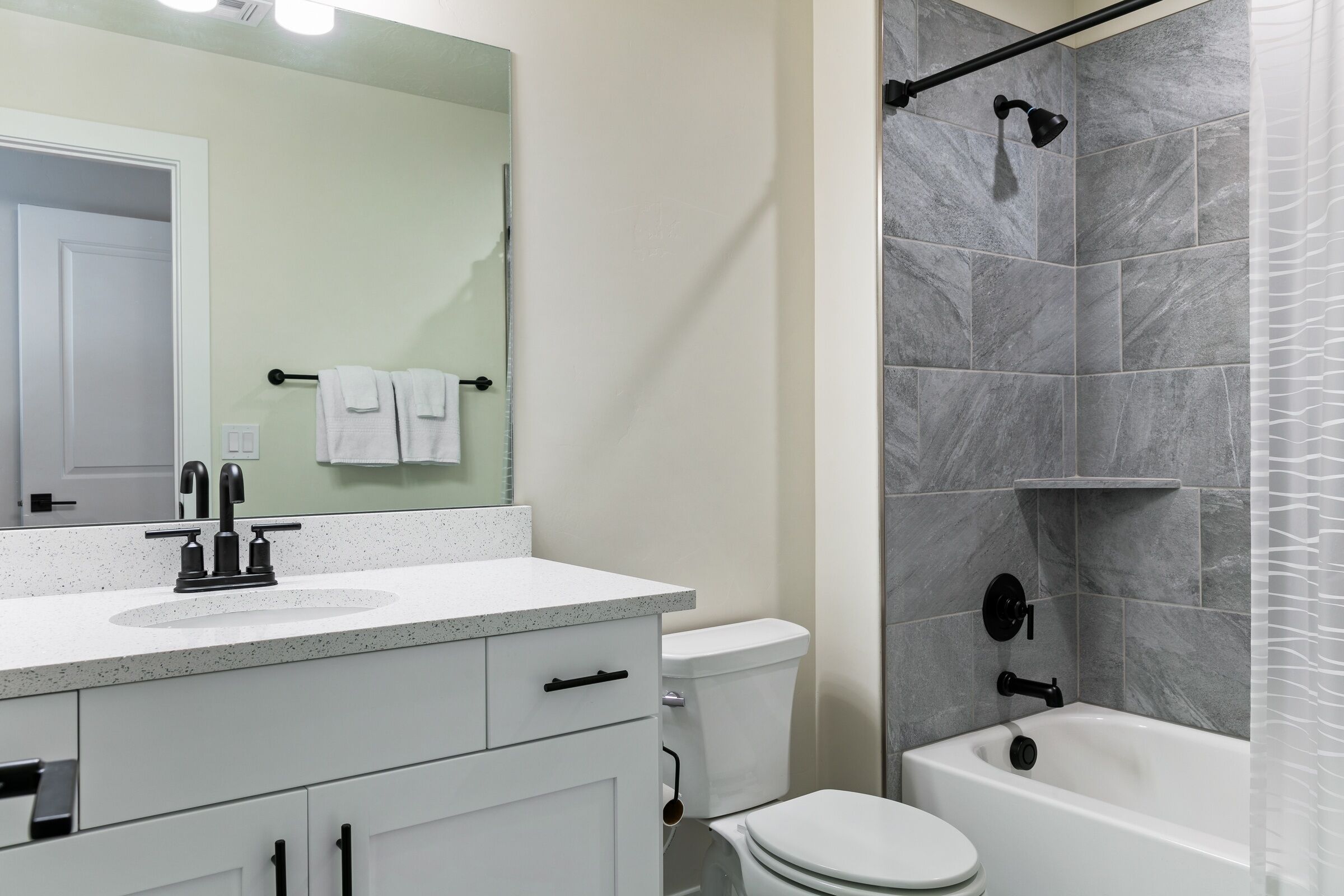 A bathroom with a white sink, a mirror, a toilet, and a bathtub.