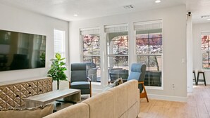 A modern living room with a large flat-screen TV, two armchairs, a sofa, and a dining area with a table and chairs. - 1 Dreamy Place by RedAwning (Washington)