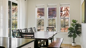 A dining area with a wooden table and chairs, large windows with a view of red rock formations, and a potted plant. - 1 Dreamy Place by RedAwning (Washington)