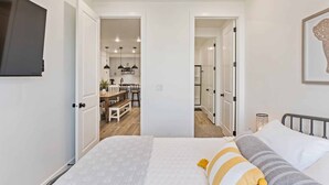 A bedroom with a bed, bedside table, and a TV mounted on the wall. - Adventures at the Cowabungalow #82 by RedAwning (St. George)