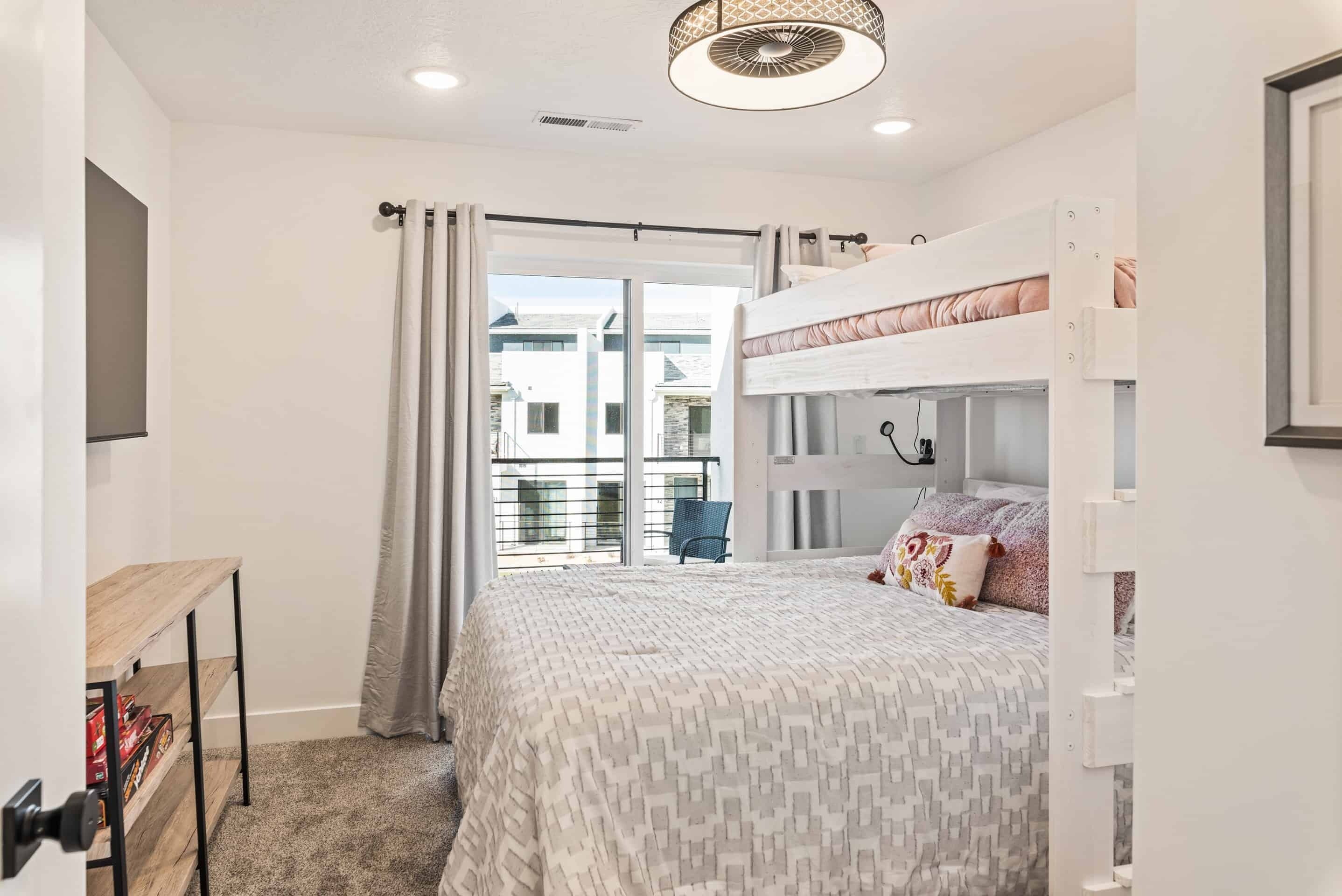 Une chambre avec un lit superposé, un bureau, une chaise et une vue sur l’extérieur.