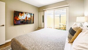 A bedroom with a large bed, a ceiling fan, a TV mounted on the wall, and a sliding glass door leading to a patio. - Relaxing Desert Botanical 2 Bedroom In Biltmore (Phoenix)