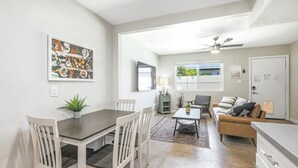 Una sala de estar moderna con un sofá, una mesa de centro y un comedor con una mesa y sillas.