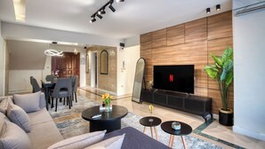 A modern living room with a sofa, coffee table, TV, and a dining area with chairs and a table. -  Prime Residence Arkadia (Cairo)
