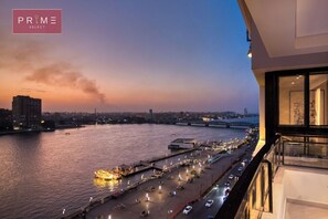 A waterfront view from a hotel balcony with a river, a bridge, and cityscape in the background.