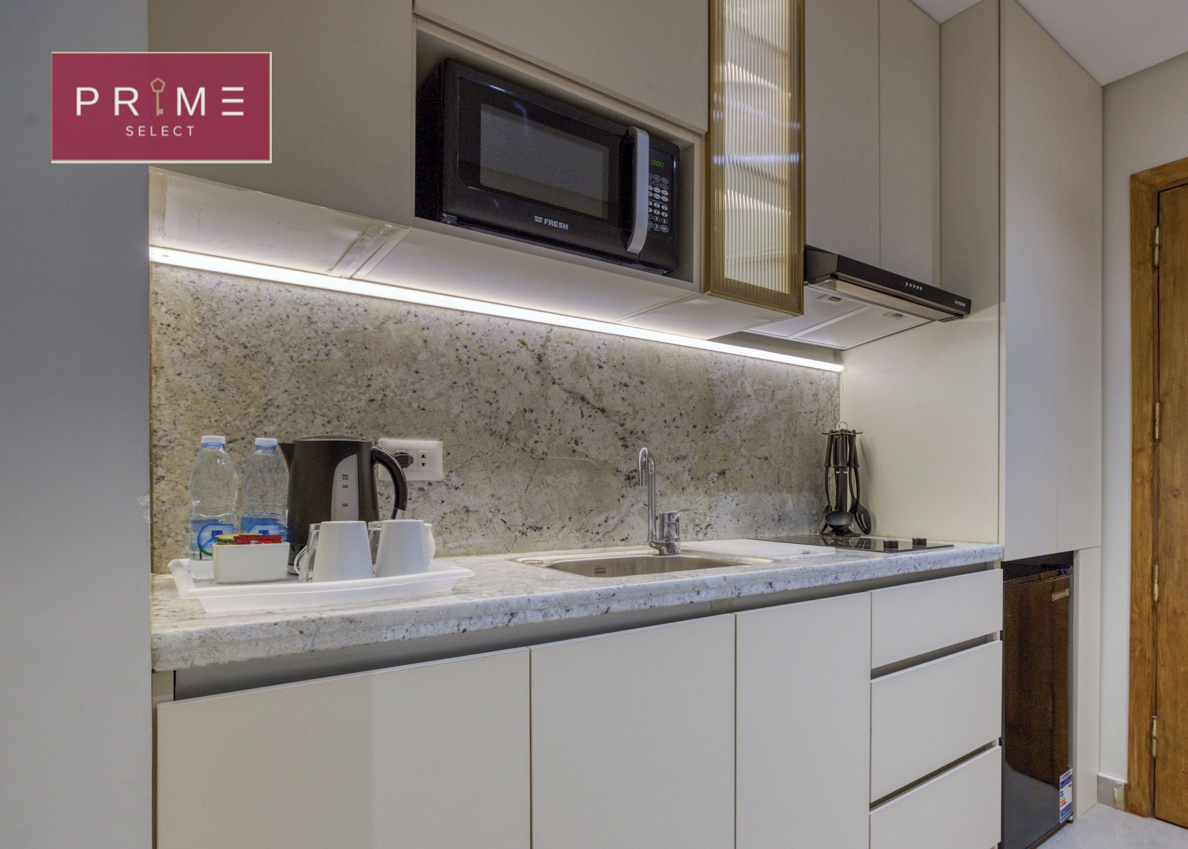 A modern kitchen with a granite countertop, a built-in microwave, a coffee maker, and a sink.