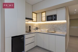 A modern kitchen with white cabinets, a built-in microwave, a coffee machine, and a dishwasher. -  Prime Residence Arkadia (Cairo)
