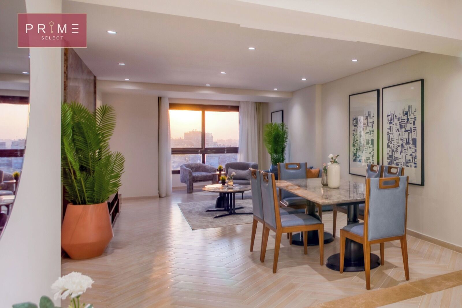 A spacious living area with a dining table, chairs, and sofas. There are large windows with a view of the city.