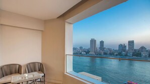 A balcony with a city view, two chairs, a small table, and a railing. -  Prime Residence Arkadia (Cairo)