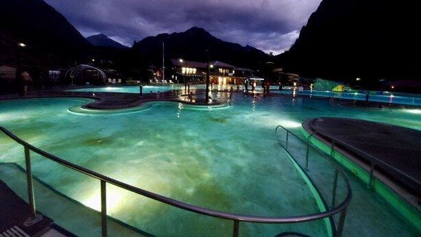 A pool area with clear water, surrounded by mountains and a building with lights. - Relax and Unwind. Location! Location! Location!Family-friendly. Outdoor space. (Ouray)