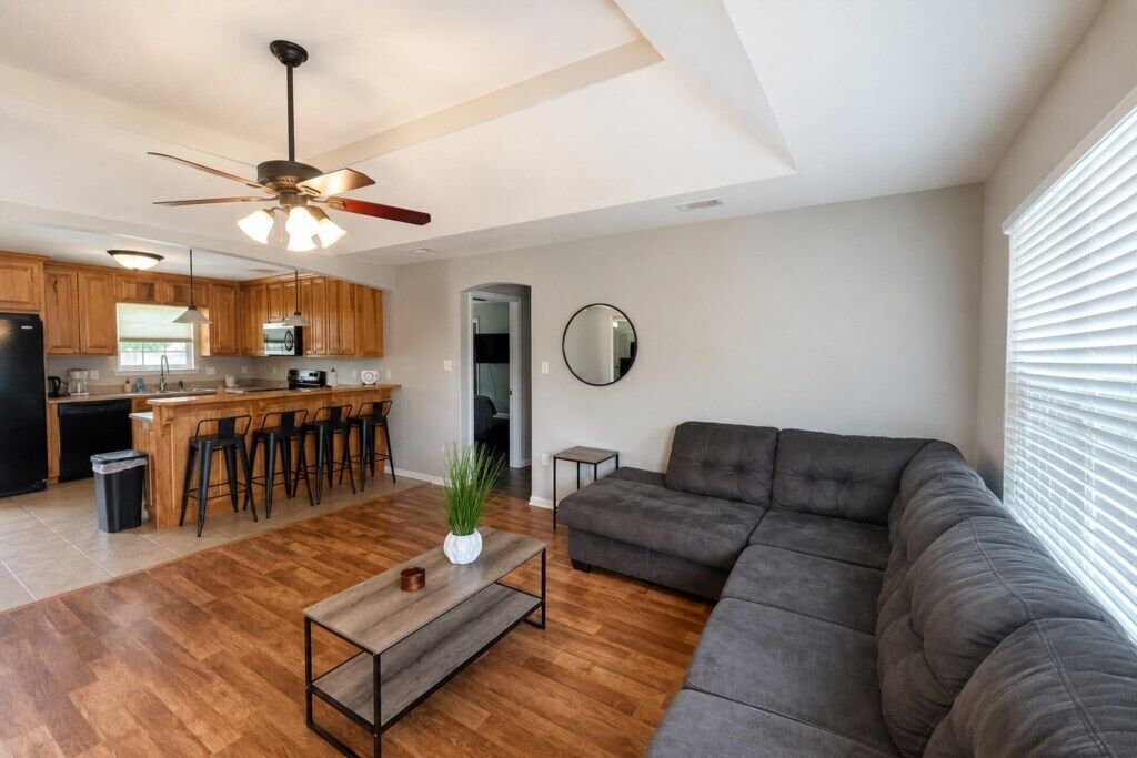 A modern living room with a sofa, a coffee table, and a ceiling fan.