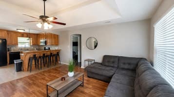 A modern living room with a sofa, a coffee table, and a ceiling fan.