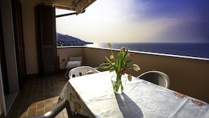 A balcony with a table, chairs, and a vase of flowers. - LE VELE BETH'S HOUSE (Brenzone sul Garda)