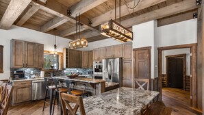 Une cuisine spacieuse dotée de meubles en bois, d’appareils électroménagers en acier inoxydable et d’un grand îlot central avec des tabourets de bar.