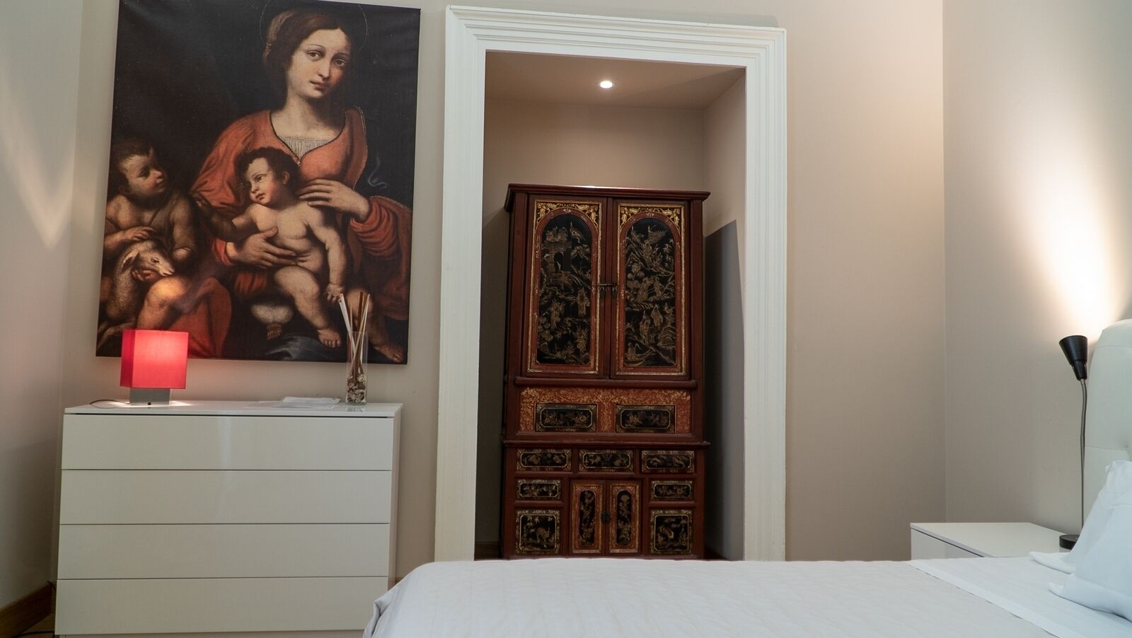 Ein Schlafzimmer mit Bett, Nachttisch, Kommode, einem Gemälde und einem Holzschrank.