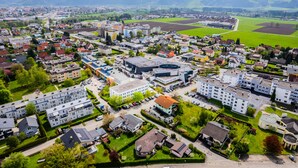 An aerial view of a town with residential buildings, a central commercial area, and surrounding green fields. - flexy.motel Spielberg (Spielberg)