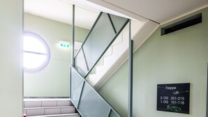 A staircase with a metal handrail and a sign indicating lift locations. - flexy.motel Spielberg (Spielberg)