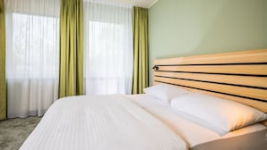 A hotel room with a large bed, green curtains, and a wooden headboard. - flexy.motel Spielberg (Spielberg)