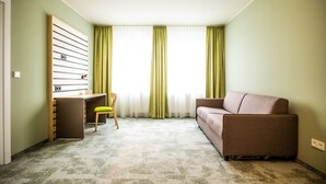 A room with a desk, a chair, a sofa, and a window with curtains. - flexy.motel Spielberg (Spielberg)