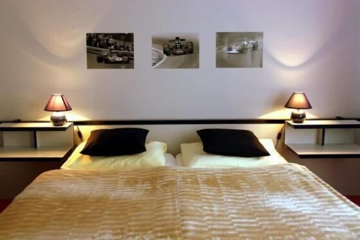 A hotel room with a bed, two bedside tables, lamps, and three wall-mounted pictures.