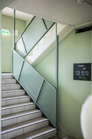 Una escalera con barandillas de metal y un cartel que indica la ubicación de los ascensores.