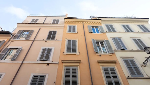 A row of multi-story buildings with uniform architectural style, featuring symmetrical window designs and shutters.