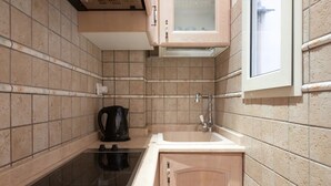 A compact kitchen with a stove, sink, and cabinet.