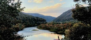A river flowing through a forested valley with hills in the background.